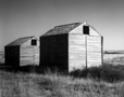 Black and white photograph of two identical grain bins titled "Twins," Oklahoma, New Mexico Boarder, architectural and landscape photography by Tony Sanders